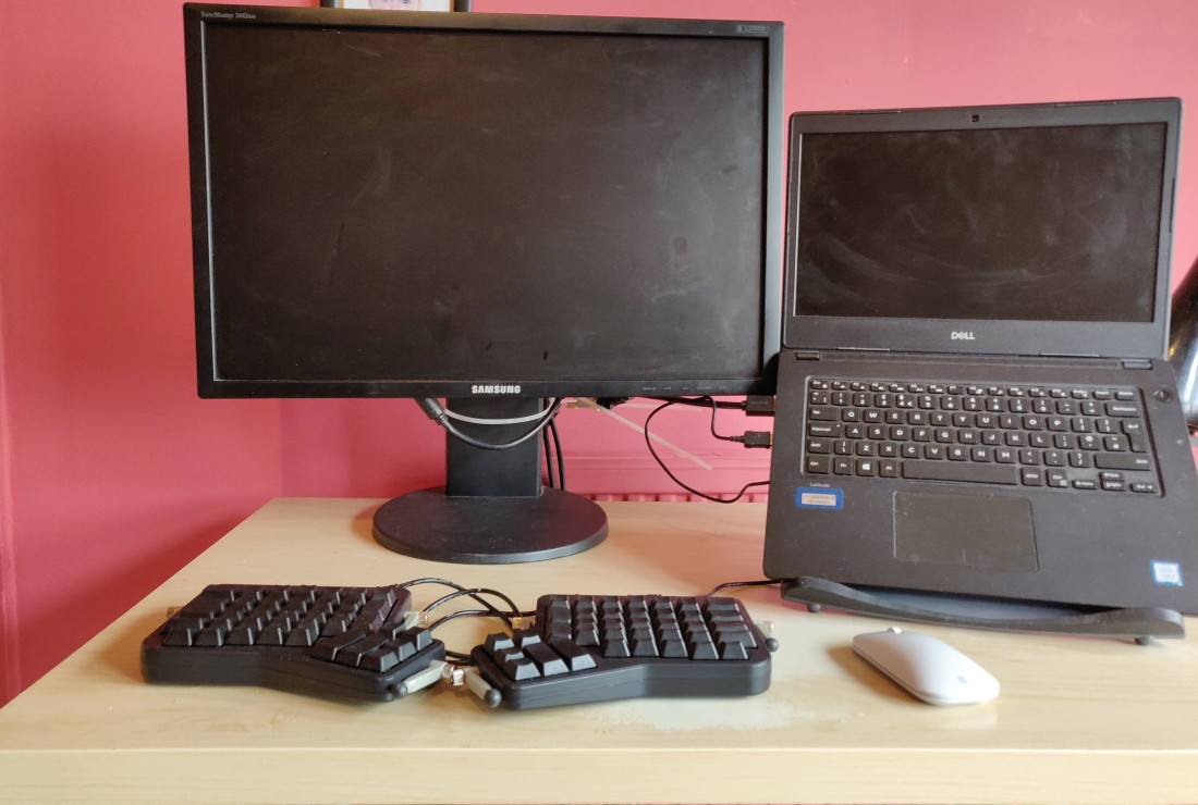 Laptop on a stand connected to a full sized monitor. The wired keyboard is and Ergodox which is paired with a wireless mouse here.